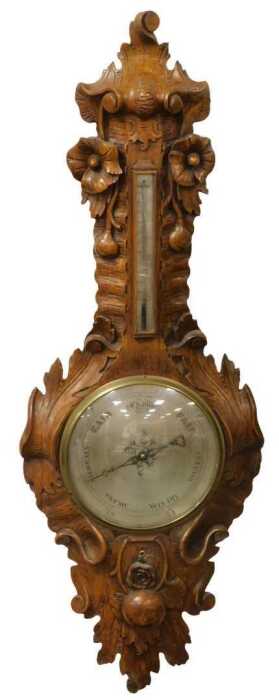 A Victorian oak wheel barometer, with a silvered dial, and thermometer, the case carved in high...