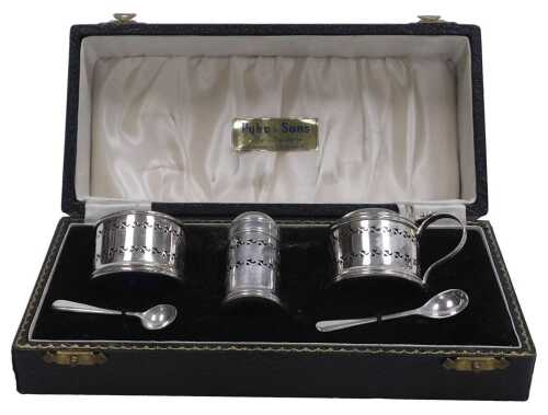 An Elizabeth II silver three piece cruet, with blue glass liners, comprising a salt cellar with...
