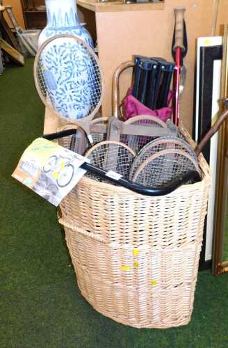 A wicker corner basket, 61cm high, 55cm wide, 44cm deep, containing bygone wooden tennis and...