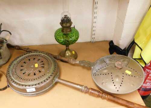 A brass and green glass oil lamp, together with two copper and brass warming pans. (3)