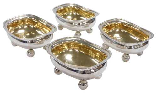 A set of four George III silver salts, crest engraved, raised on ball feet, Solomon Hougham,...