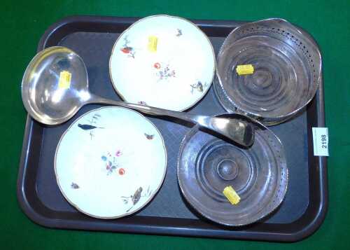 A pair of plated wine coasters, together with a ladle, and two 19thC porcelain saucers.