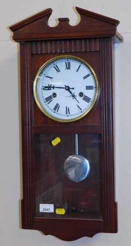 A wooden wall clock, with a 31-day regulator, decorative pediment, and a pendulum swing.