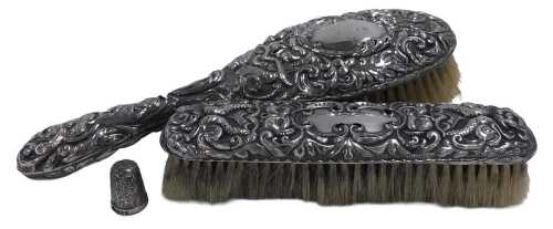 An Edward VII silver backed hairbrush and clothes brush, embossed with masks, serpents, and...