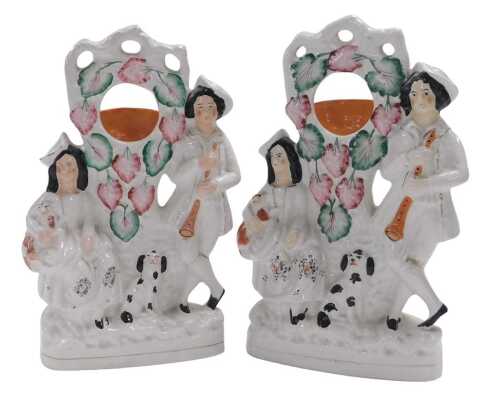 A pair of late 19thC Staffordshire pottery watch holders, modelled with a musician and seated...