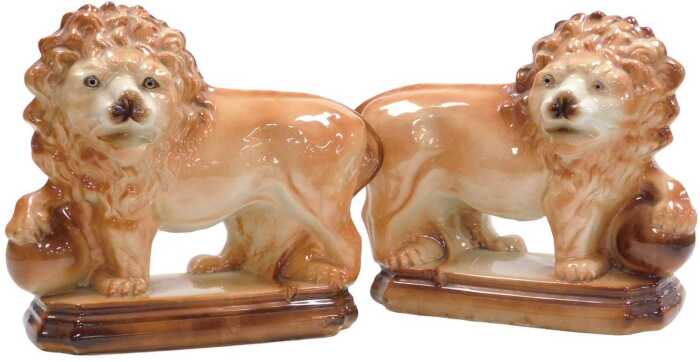 A pair of 20thC Staffordshire pottery lions, each modelled resting a front paw on a ball, on a...