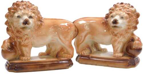 A pair of 20thC Staffordshire pottery lions, each modelled resting a front paw on a ball, on a...