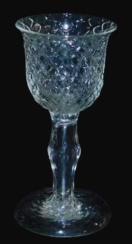A Georgian glass goblet, with a honeycomb moulded bowl, above a plain bulbous stem over a...