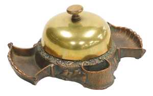 A late 19thC cast copper and brass hotel desk bell and match strike, stamped to underside Russel...