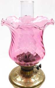 A Victorian brass oil lamp, the wrythen cranberry tinted shade, above a leaf decorated reservoir... - 2