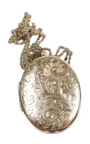 A 9ct gold oval photo locket, with engraved foliate decoration, on a neck chain with bolt ring...