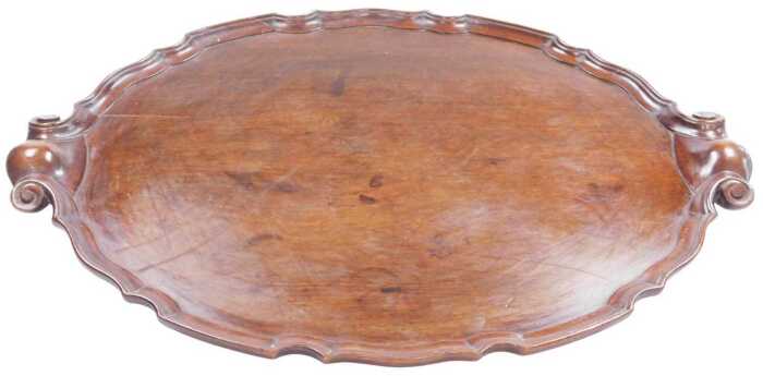 A George III style mahogany oval tray, with a piecrust border and scroll handles, 68cm x 49.5cm.