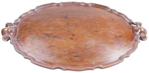 A George III style mahogany oval tray, with a piecrust border and scroll handles, 68cm x 49.5cm.