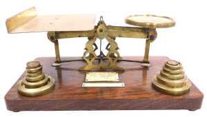 An early 20thC oak and brass set of postal scales, with ivorine plaque for Inland Letter Rates,...