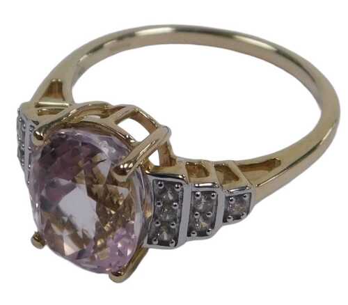 A 9ct gold morganite and diamond ring, the oval and cut morganite, high claw set, flanked by...