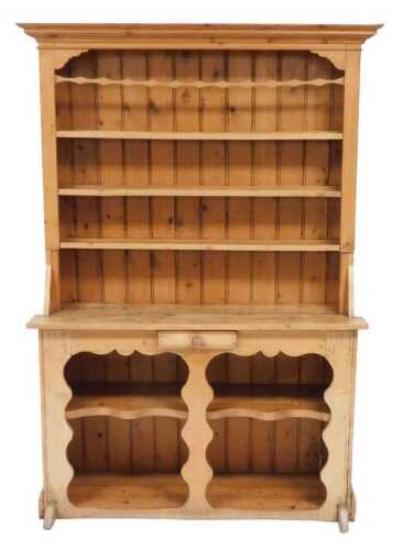 A pine dresser, the outswept pediment above three shelves, over a base with a small frieze...