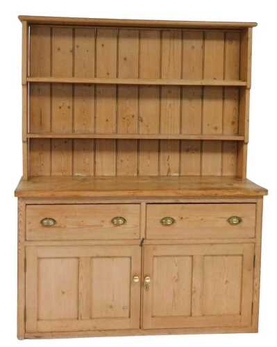 A Victorian pine dresser, the pediment over a two shelf plate rack, above a base with two...