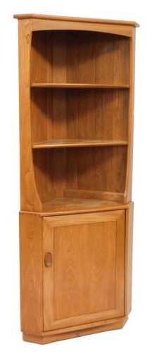 An Ercol light elm corner display cabinet, the pediment over two shelves, above a cupboard,...