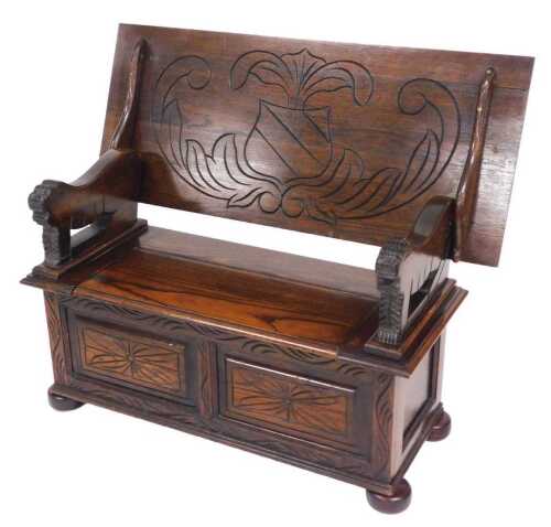 An early 20thC oak monk's bench, the top carved with a flower, raised on arms with lion carved...
