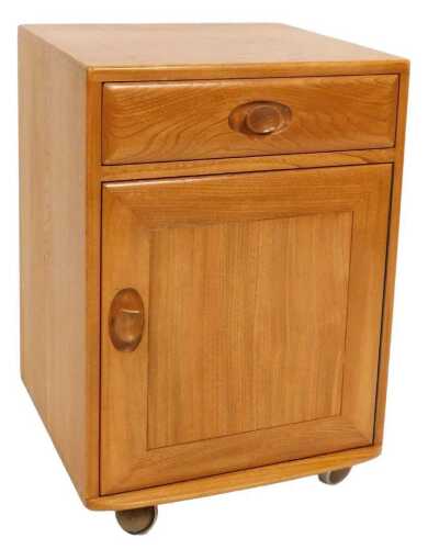 An Ercol light elm side cupboard, with a frieze drawer over a cupboard door enclosing a single...