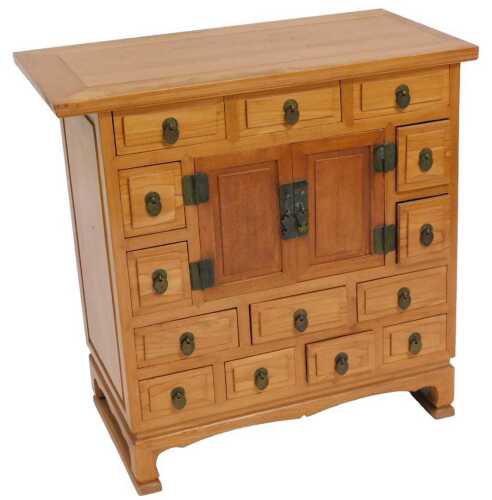 A Japanese elm tansu chest, with a pair of central doors surrounded by fourteen frieze drawers,...