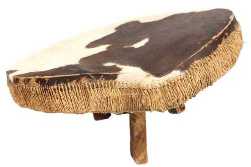 An African cow hide drum, raised on three vari-sized legs, maximum height 49cm, 94cm wide.