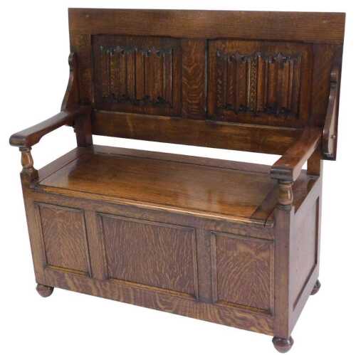 An early 20thC oak monk's bench, with a hinged linen fold panelled back, and a hinged seat,...