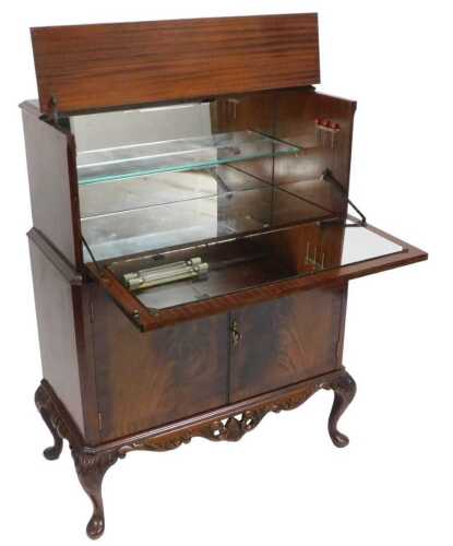 A late 20thC mahogany cocktail cabinet, with a hinged lid and front, opening to reveal a glass...