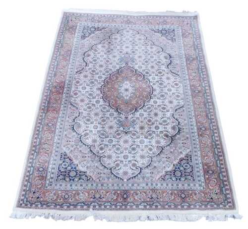 A Persian red and cream ground rug, the central field decorated with radiating and repeating...