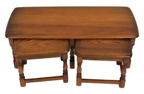 An Ercol elm nest of occasional tables, each raised on baluster turned supports, united by box...
