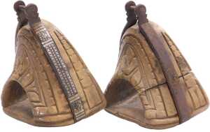 A pair of 19thC Chilean carved wooden huaso stirrups, each with iron mounts, decorated with a...
