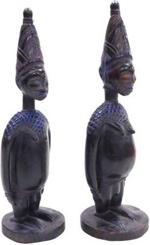 A pair of African Yoruba fertility figures, each with a tapering hat, and circular base,...