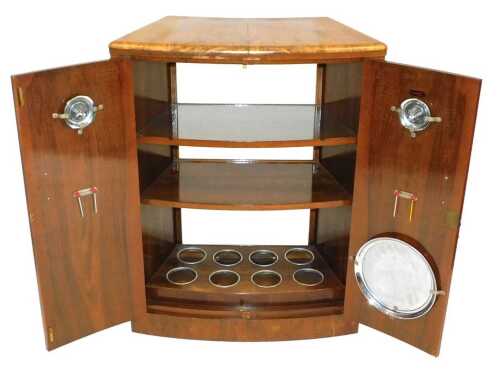 A 1950s Turnidge walnut bow fronted cocktail cabinet, the two doors opening to reveal two...