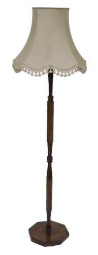 An early 20thC oak standard lamp, with a pale green shade, above a turned column, on an...