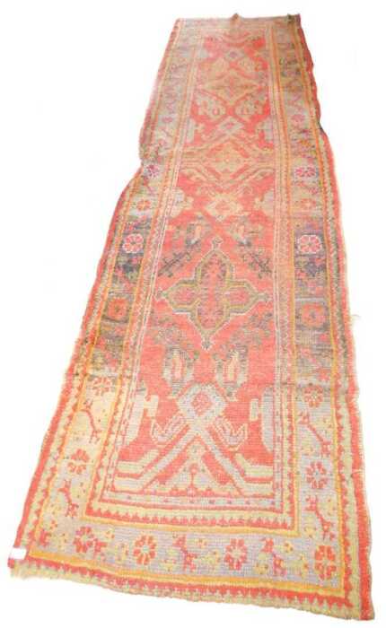 A Turkish runner, with a geometric design, in shades of black, pale blue and green, on a red...