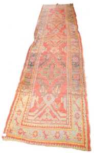A Turkish runner, with a geometric design, in shades of black, pale blue and green, on a red...