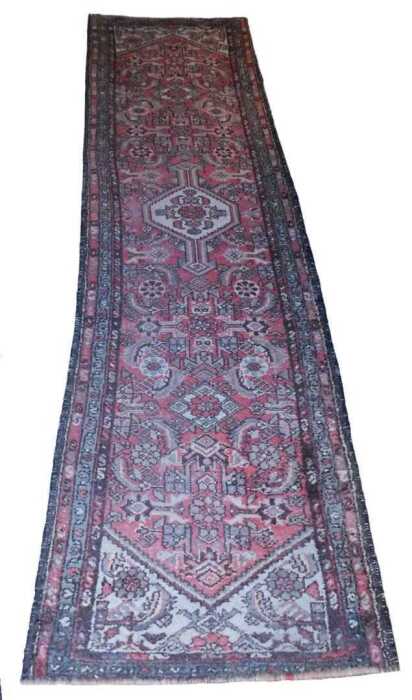 A Persian runner, with a central cream pole medallion, on a red ground decorated with roundels,...