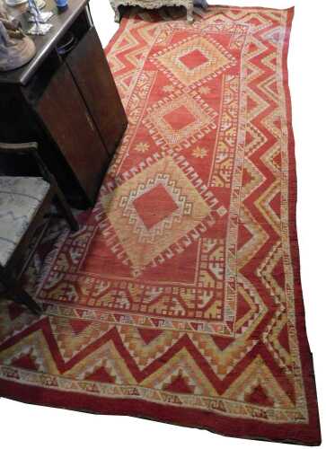 A Turkish rug, with a design of three latch hook lozenges, on a red ground, one wide and two...