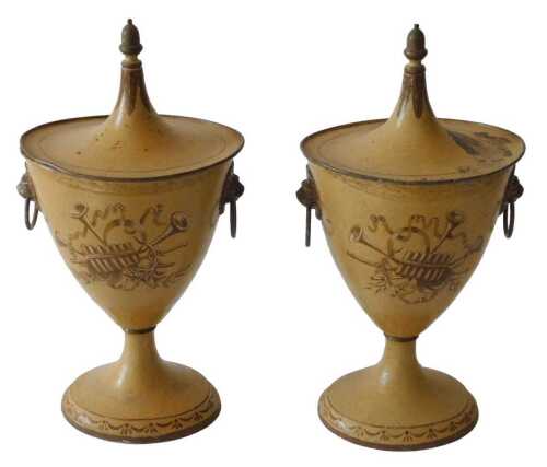 A pair of beige painted toleware two handled urns and covers, with a tapering lid, the base...