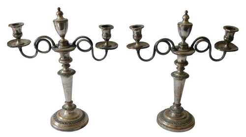 A pair of silver plated two branch candelabras, with central urn, tapering column and domed feet,...