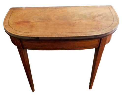 A George III mahogany and ebony strung tea table, the D shaped top hinged to reveal a polished...
