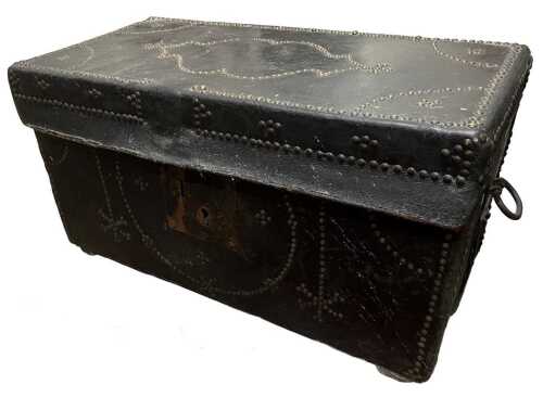 An early 19thC leather bound travel trunk, with iron side carrying handles, and studded...