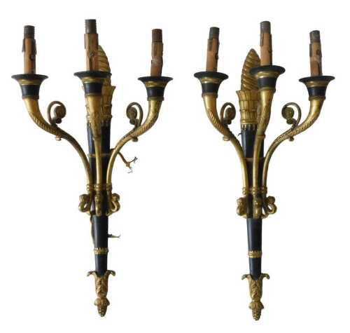 A pair of Empire style gilt brass and ebonised three branch wall lights, each cast with flowers,...