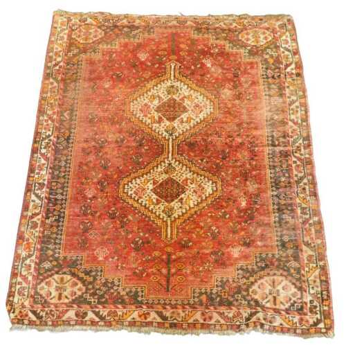 A Persian rug, with a pole medallion, on a red ground decorated with flowers, one wide and two...