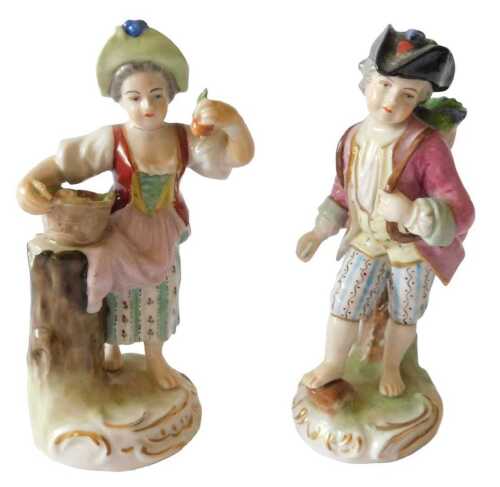 A pair of early 20thC German porcelain figures, one of a lady with a basket of fruit, the other...