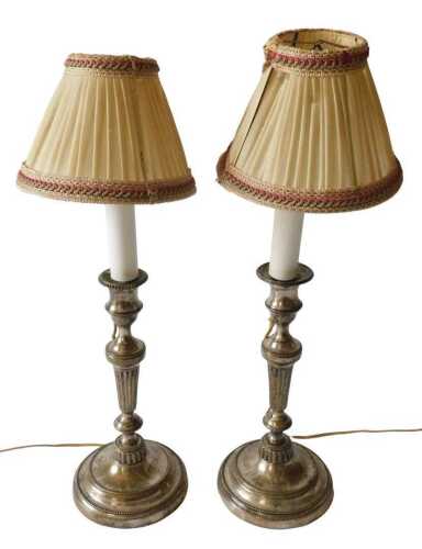 A pair of silver plated candlesticks, each with a part fluted column, on a domed foot, later...