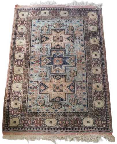 An Eastern carpet, with three medallions, on a pale blue ground, one wide and two narrow borders,...