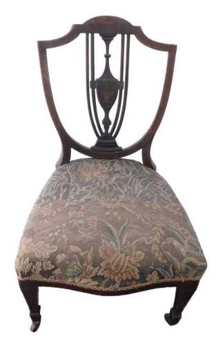 An Edwardian mahogany nursing chair, with a padded seat, on square tapering legs with castors....