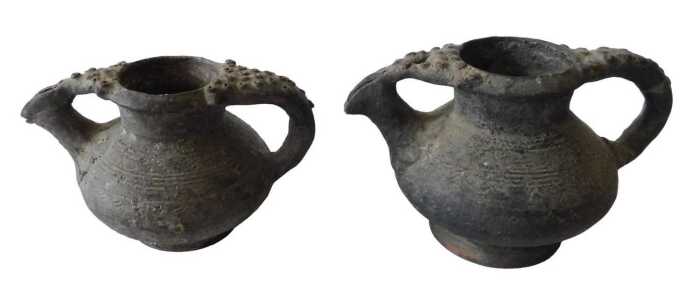 A Continental black glazed terracotta jug, the border and handle decorated with roundels, 15cm...