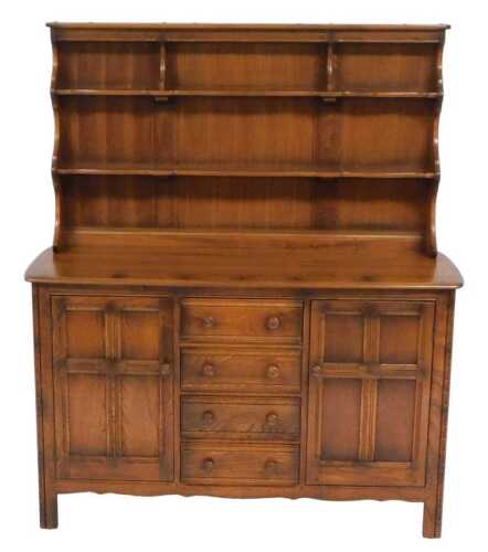 An Ercol elm dresser, the plate rack with two shelves, above a base of four drawers, flanked by...
